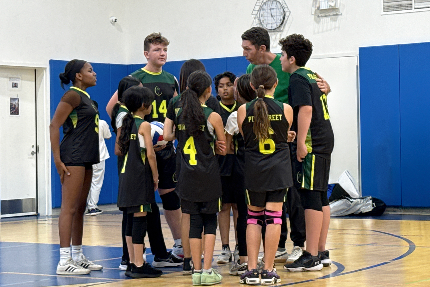 Pine Street School's volleyball team gathers in a huddle with their coach during a game