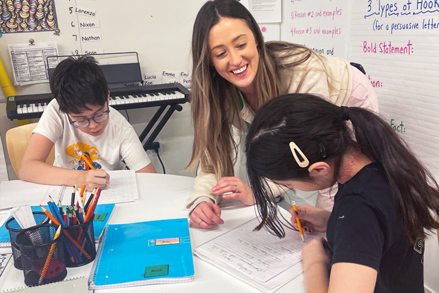 A teacher working with two students in the classroom