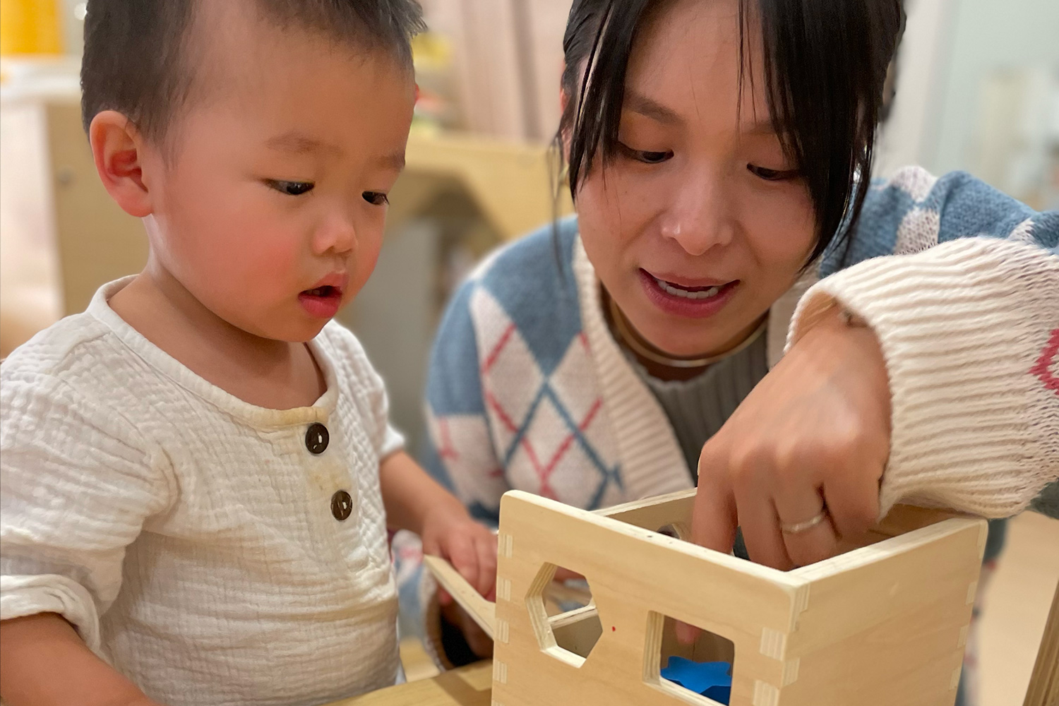 A Pine Street parent with her child working on a wooden shape activity 