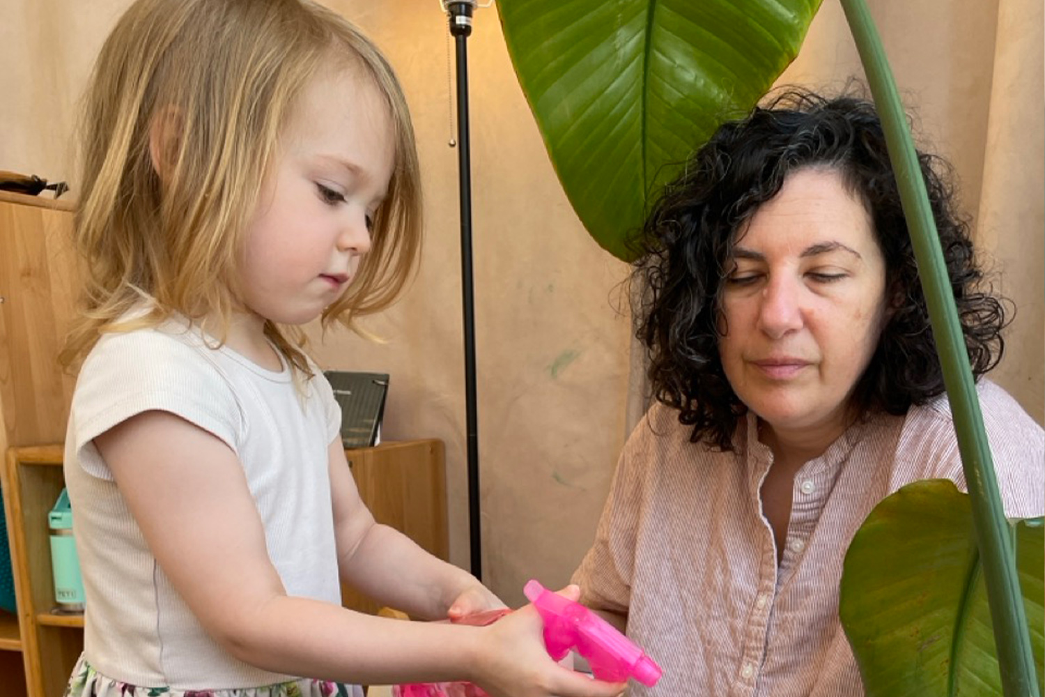 Montessori practical life moment in the classroom - a student learning to take care of plants guided by her teacher