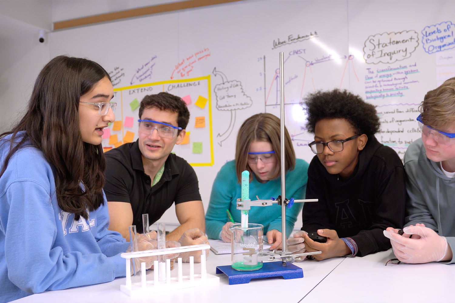 Four middle school students and their Science Teacher gather around the science experiment in the Middle School Science Lab at Pine Street School
