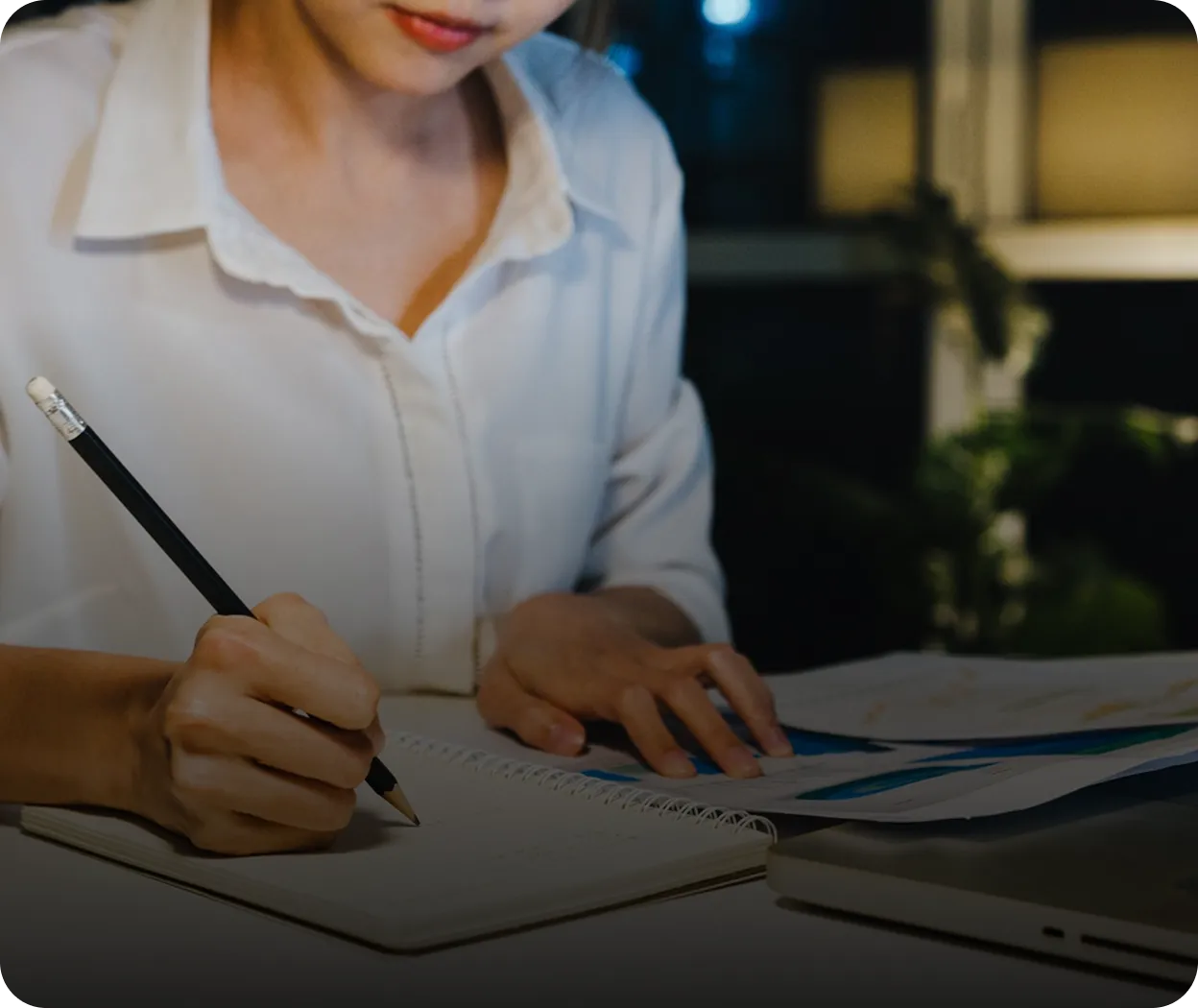 Business professional taking notes while reviewing documents at a desk