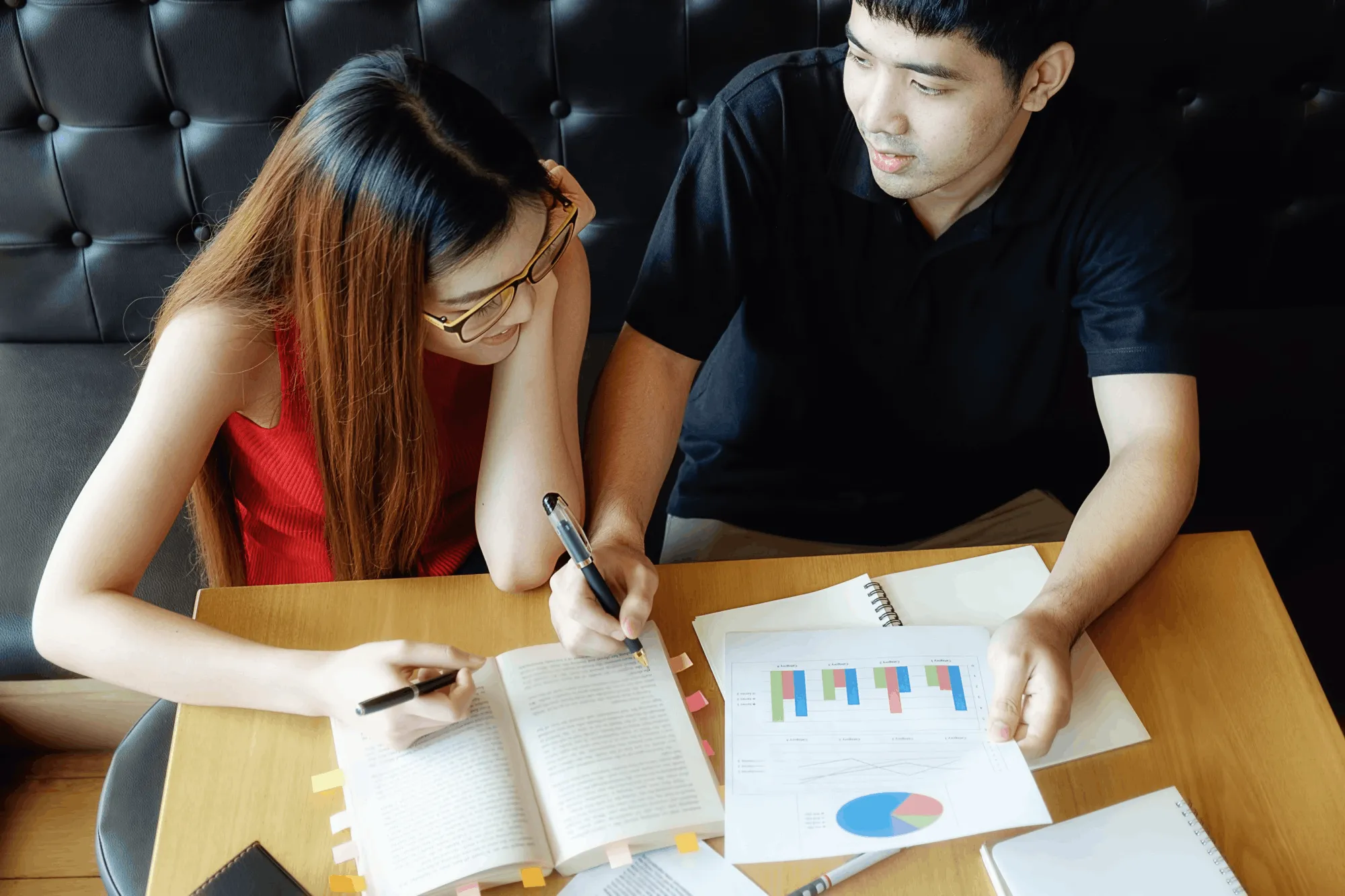 Two professionals reviewing reports and business data during a strategy meeting
