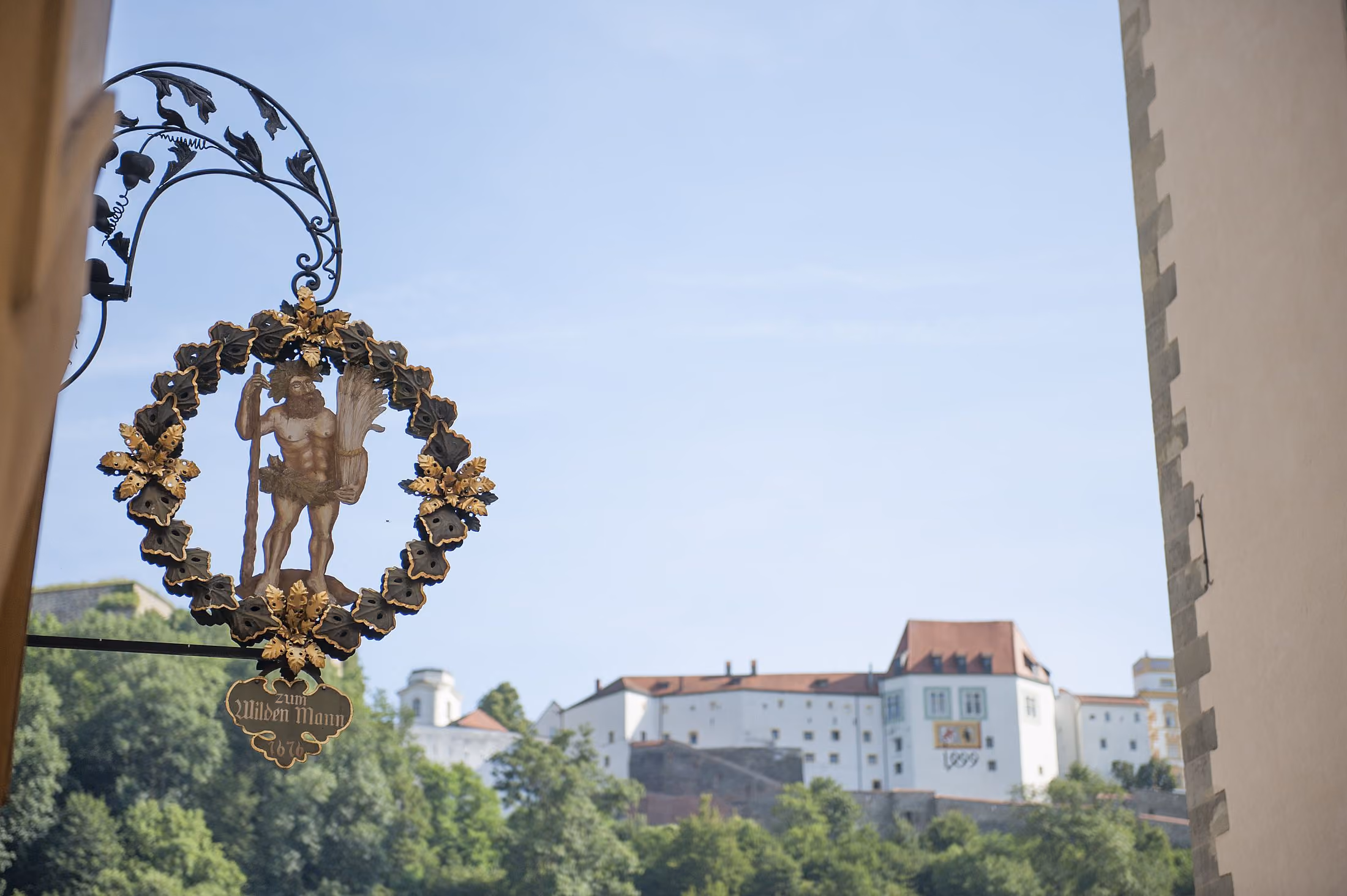 Schmiedeeisernes Schild des Hotels Wilder Mann mit der Veste Oberhaus in Passau