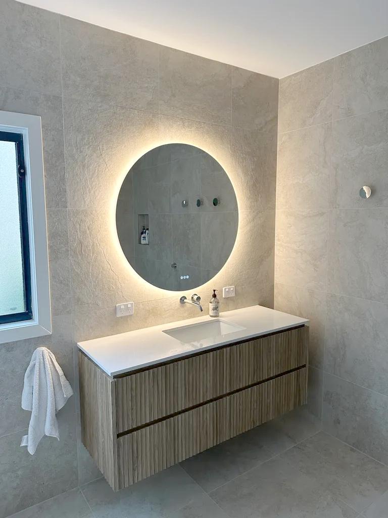 Backlit bathroom mirror and electrical fittings in a residential renovation.
