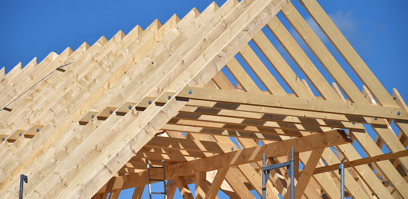 Dachstuhl aus Holzrahmen im Bau vor blauem Himmel.