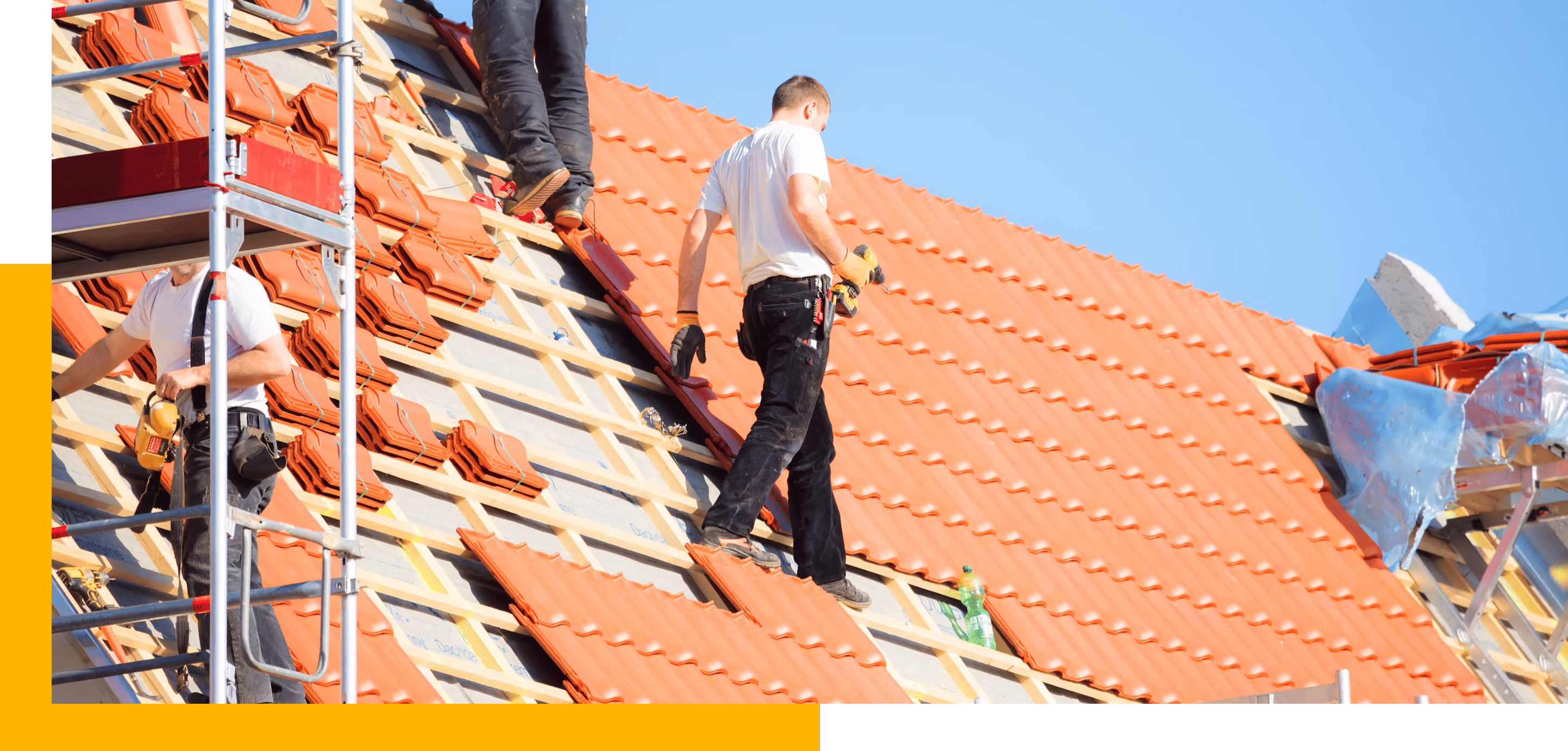 Zwei Handwerker montieren rote Dachziegel auf einem Dach bei sonnigem Wetter.