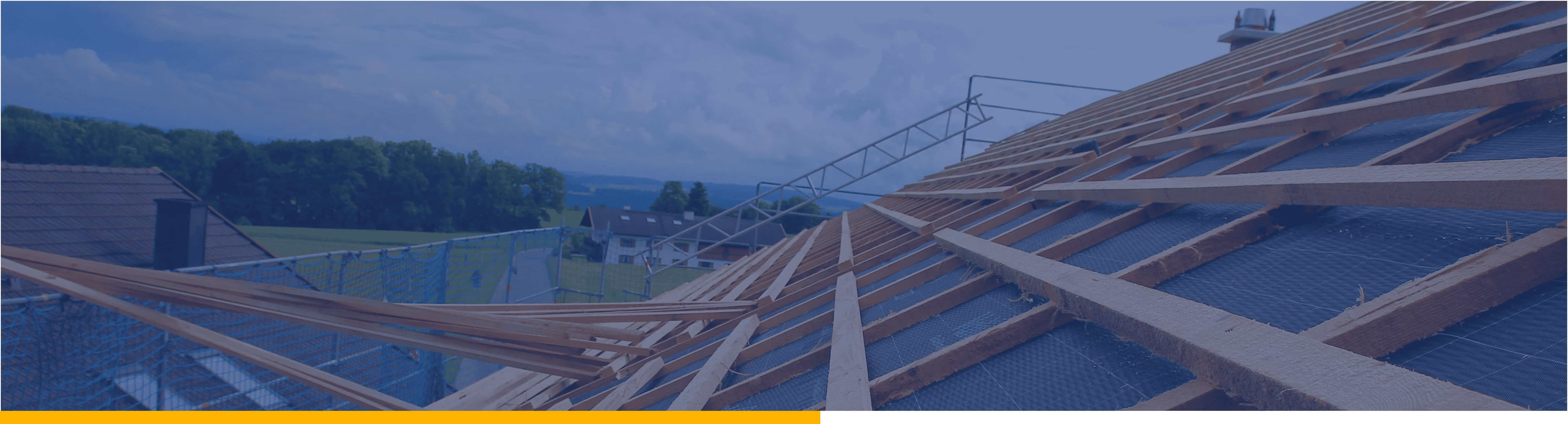 Dachkonstruktion aus Holzrahmen auf einem Haus während einer Bauphase unter blauem Himmel.