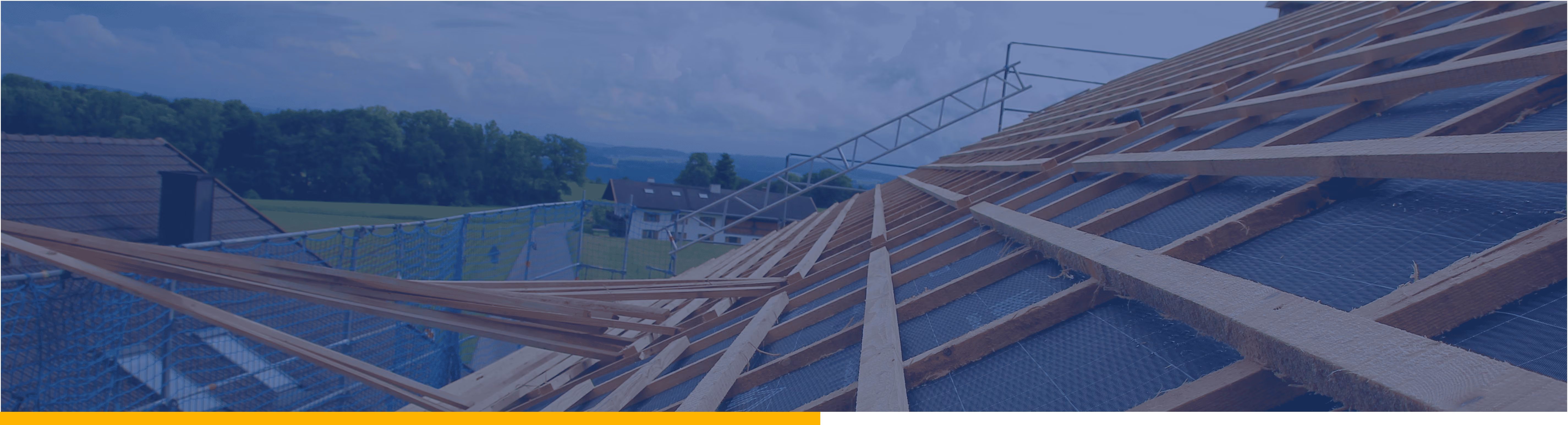 Halbfertiges Holzrahmendach auf einem Haus in ländlicher Umgebung mit Schutznetz.