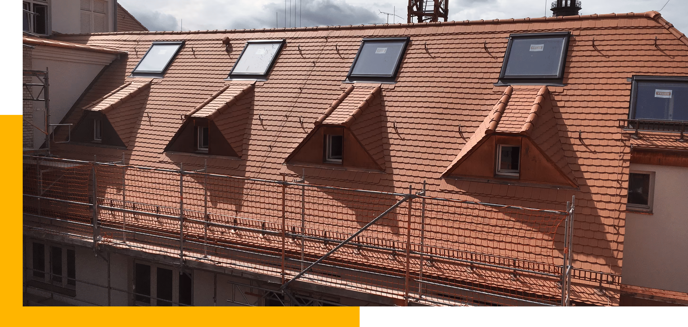 Hausdach mit fünf modernen Dachfenstern und Gerüst davor unter bewölktem Himmel.