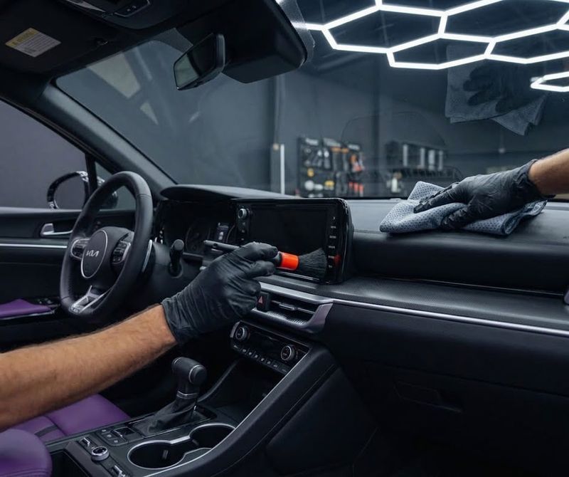 Detailer cleaning a dashboard air vent with a brush