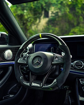 Custom carbon fiber and Alcantara steering wheel with a yellow center stripe in a Mercedes-Benz