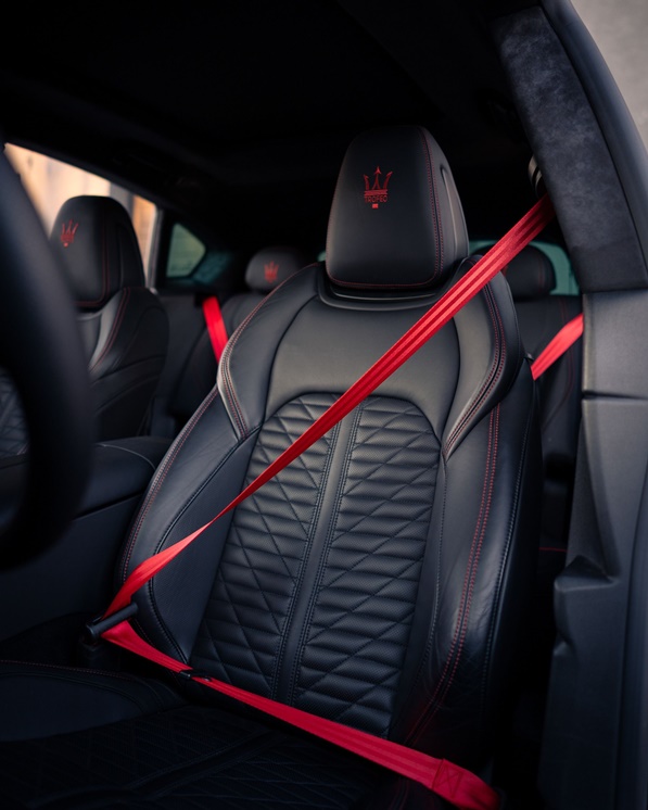 Red custom seat belts installed in a quilted leather interior
