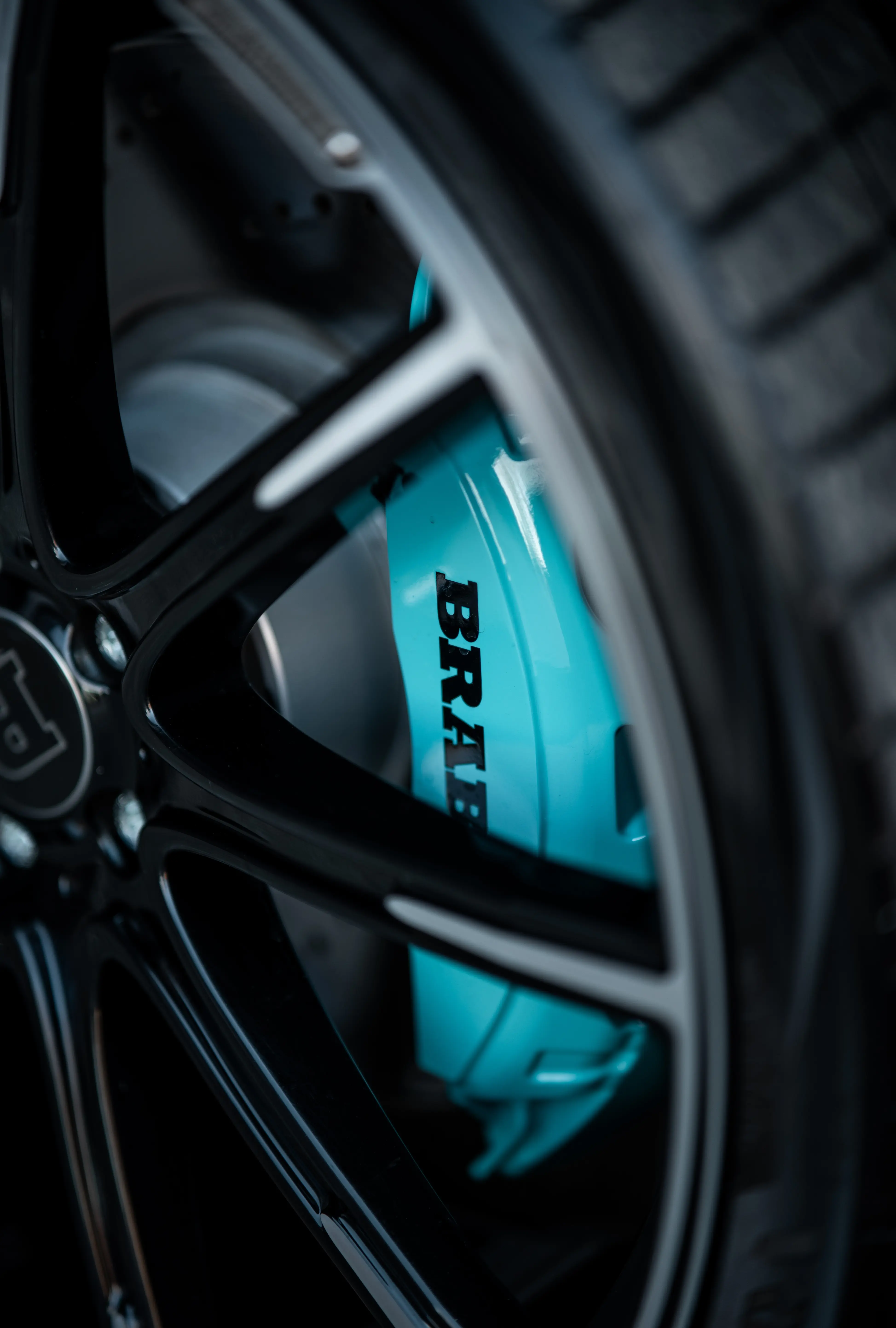 Teal painted Brabus brake caliper seen through a black wheel
