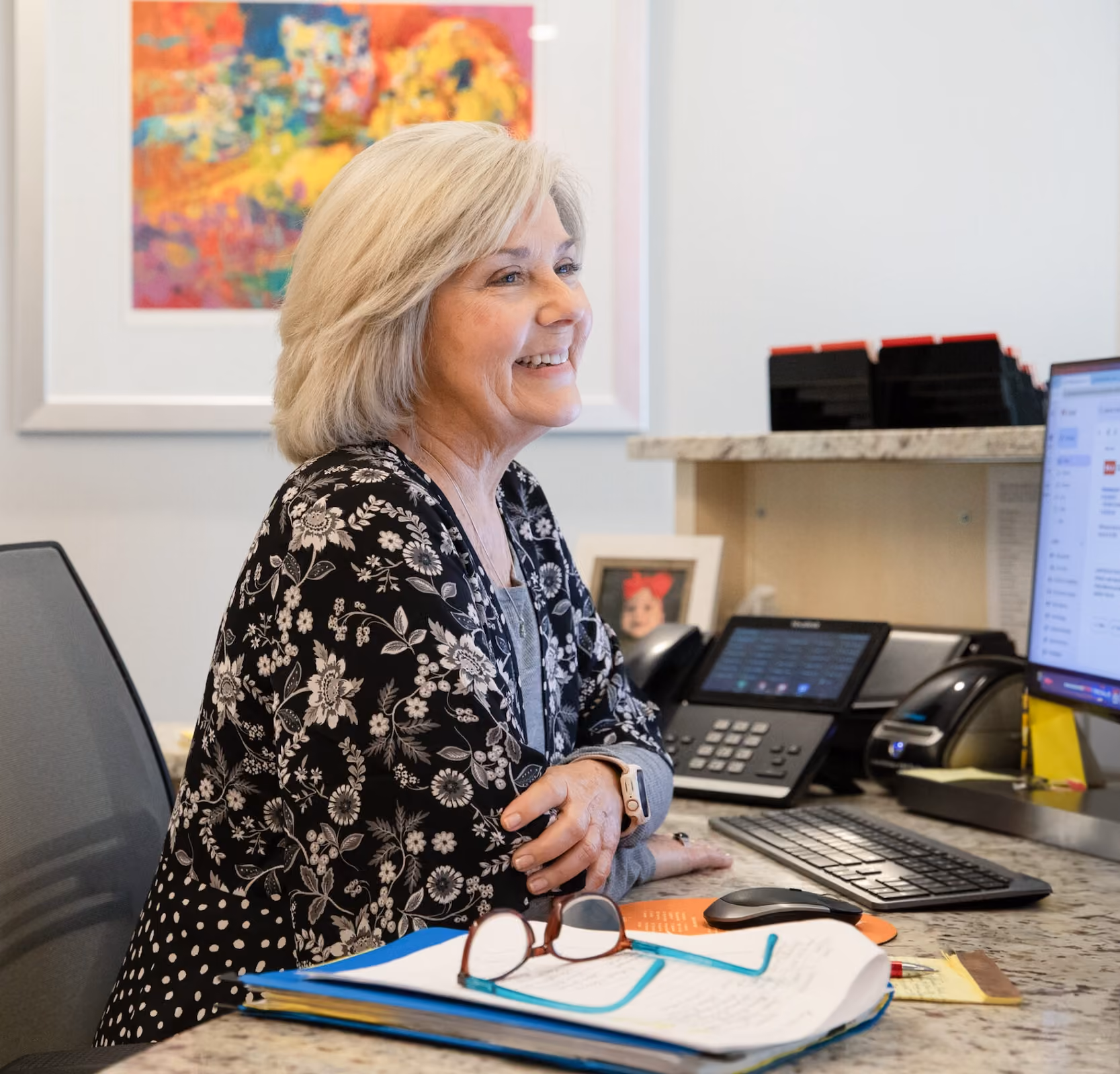 A woman smiling at a desk in an office