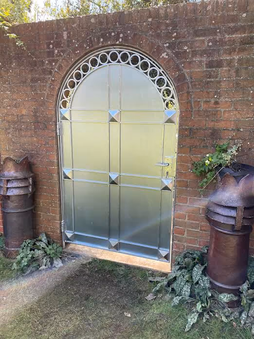 A metal door set in a brick wall with decorative posts on either side.