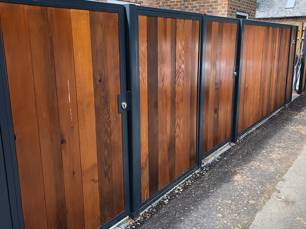 Four wooden doors with metal frames stand aligned on pavement.