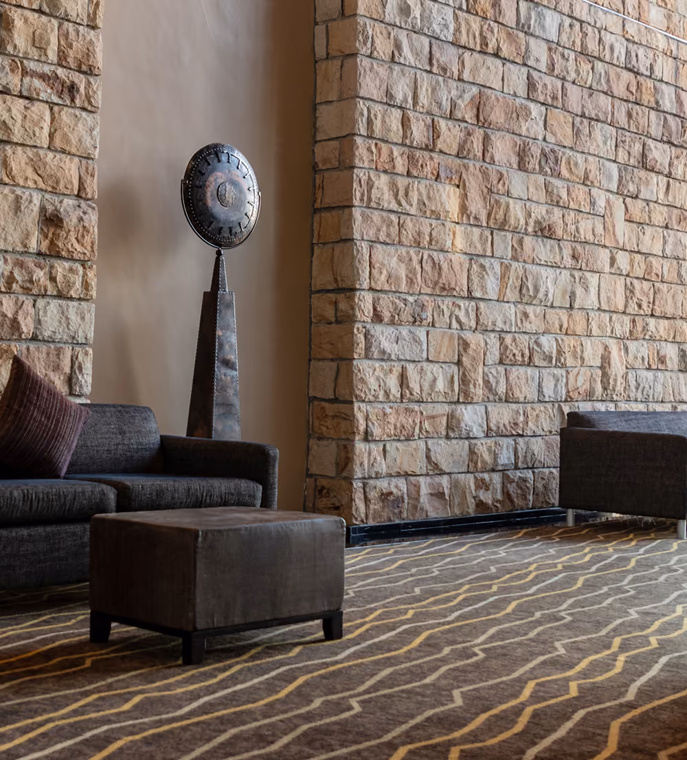 A modern lounge area with a dark sofa, matching armchair, and a decorative metal sculpture.