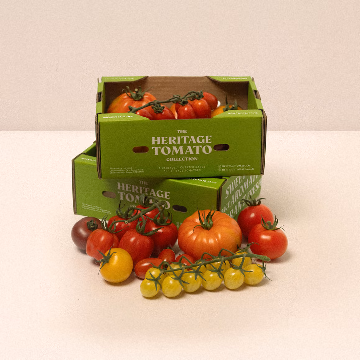 Variety of heirloom tomatoes in red, yellow, and orange in green boxes labeled The Heritage Tomato Collection.