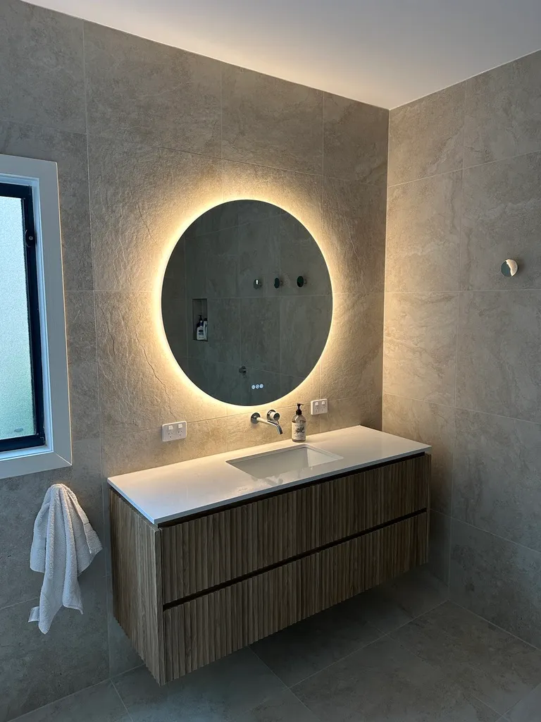 Backlit bathroom mirror and electrical fittings in a residential renovation.