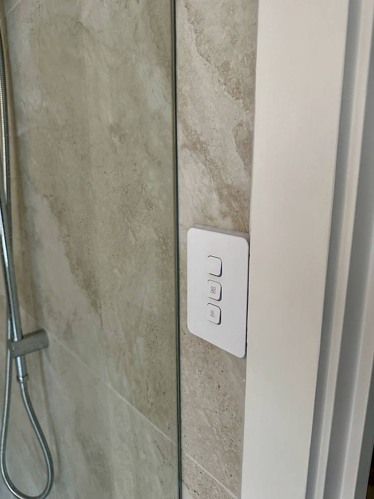 A modern switch plate installed on a tiled wall.