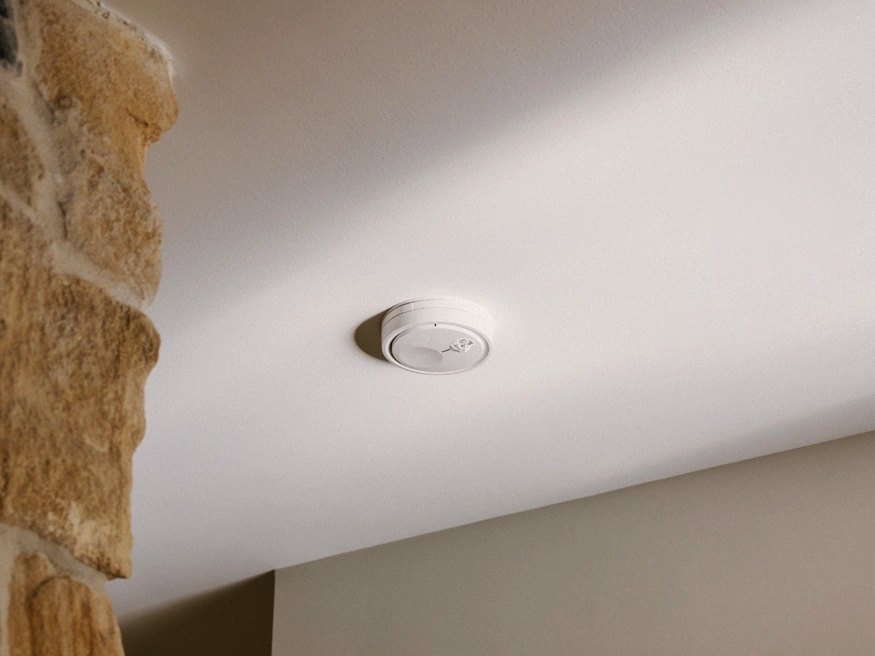 A hard-wired smoke alarm installed on a ceiling.