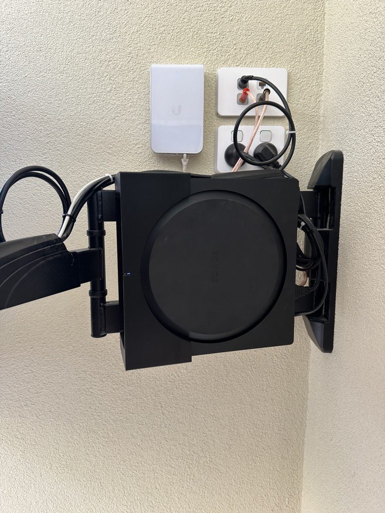 A Sonos amplifier and tidy cabling in the cabinet behind a wall-mounted TV.