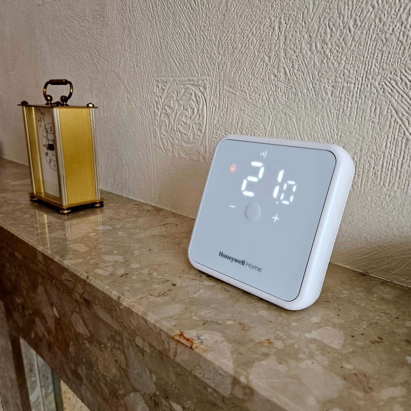 Honeywell Home thermostat displaying 21.10 degrees on a marble countertop