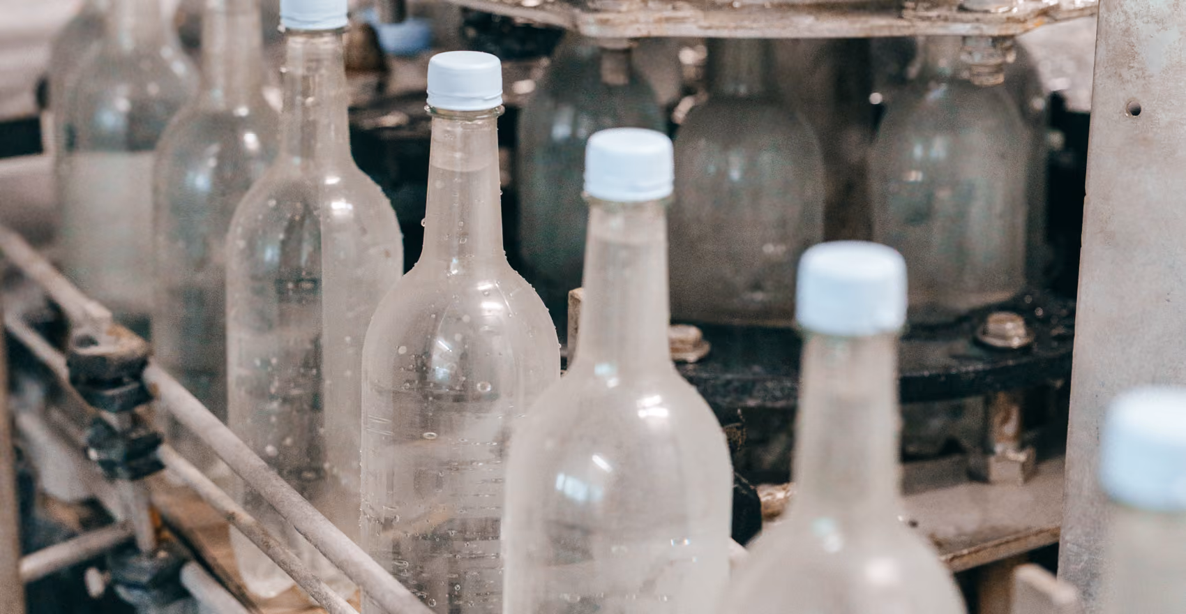 Bouteilles en plastique transparent alignées sur une machine dans une chaîne d'embouteillage.
