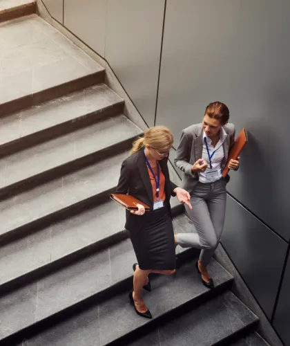 Two professionals with conference badges talking on a staircase