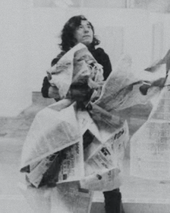 Black and white photo of a woman kneeling and smoothing fabric on the floor in a workshop.