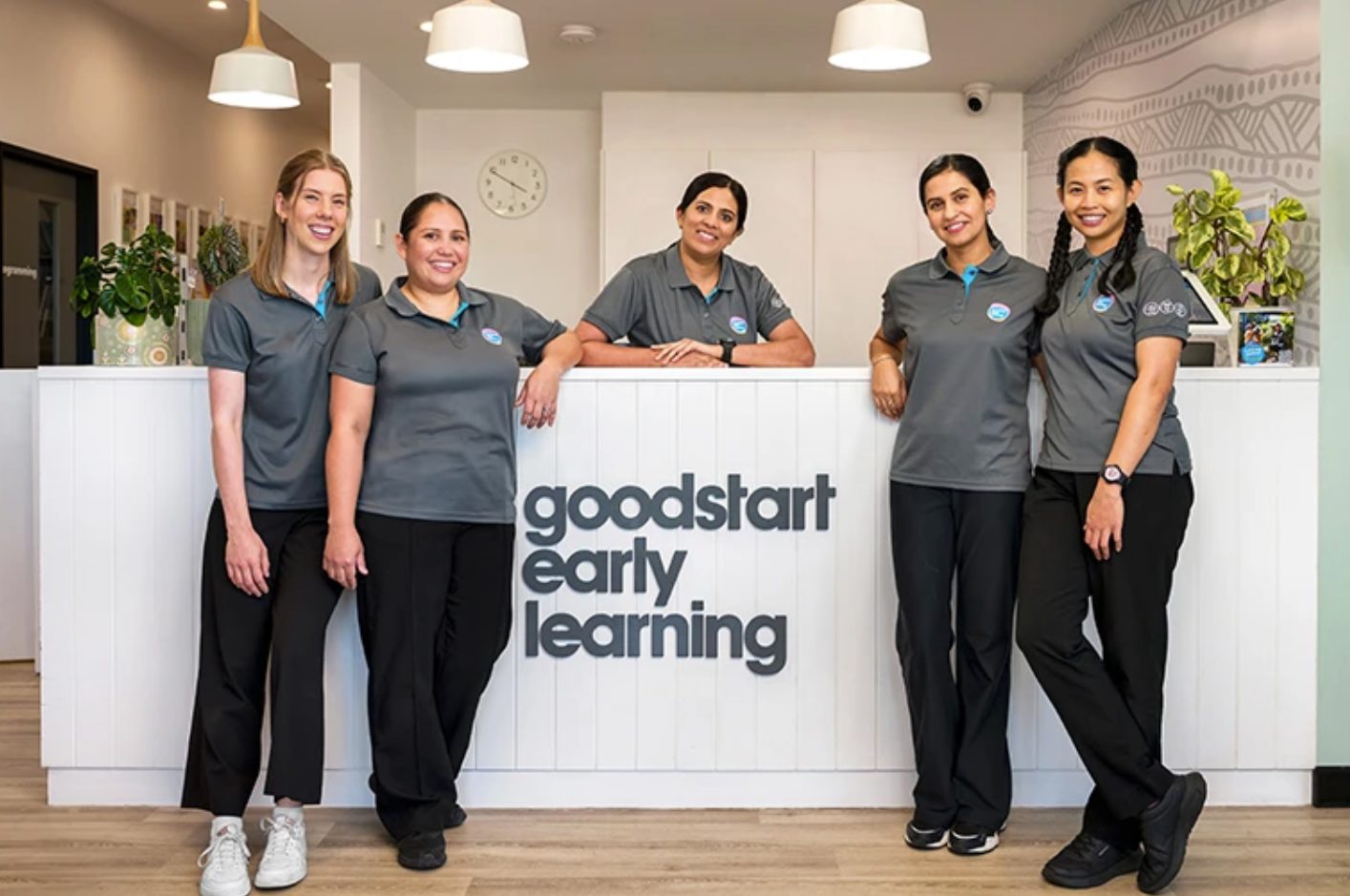 Goodstart Early Learning team standing behind a centre reception desk