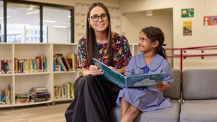 Educator reading with a primary school student in a school library