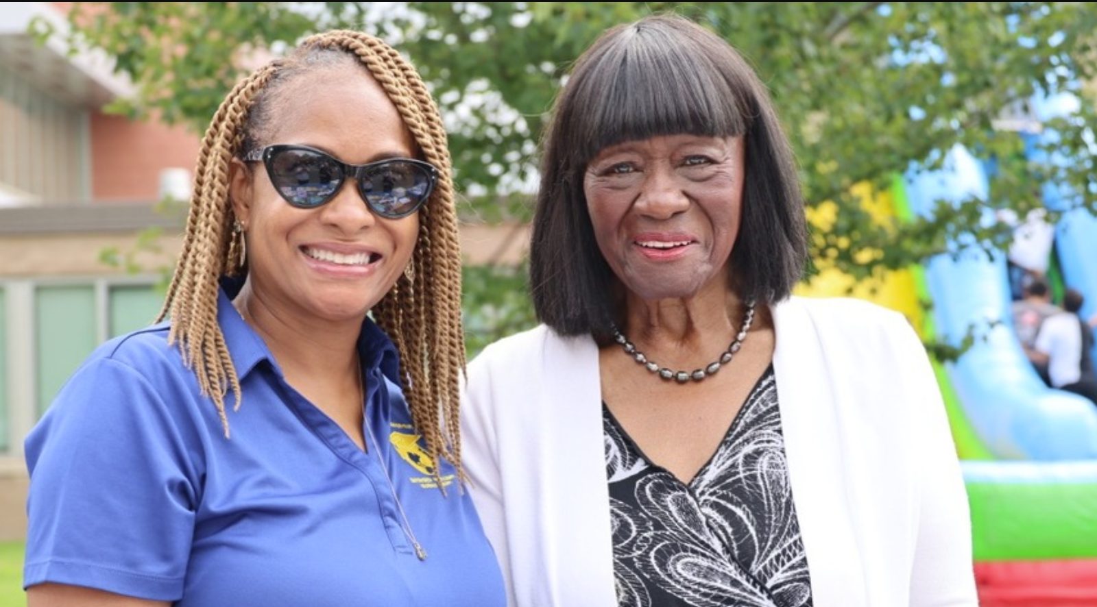Two educators smiling together outdoors at a school event
