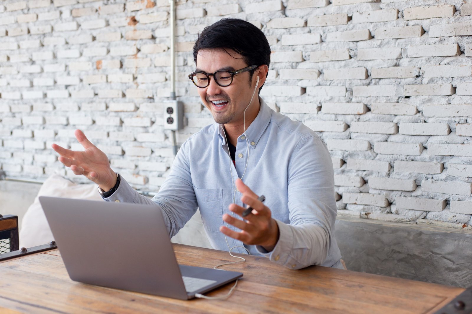 A man talking and gesturing during a video call at a laptop