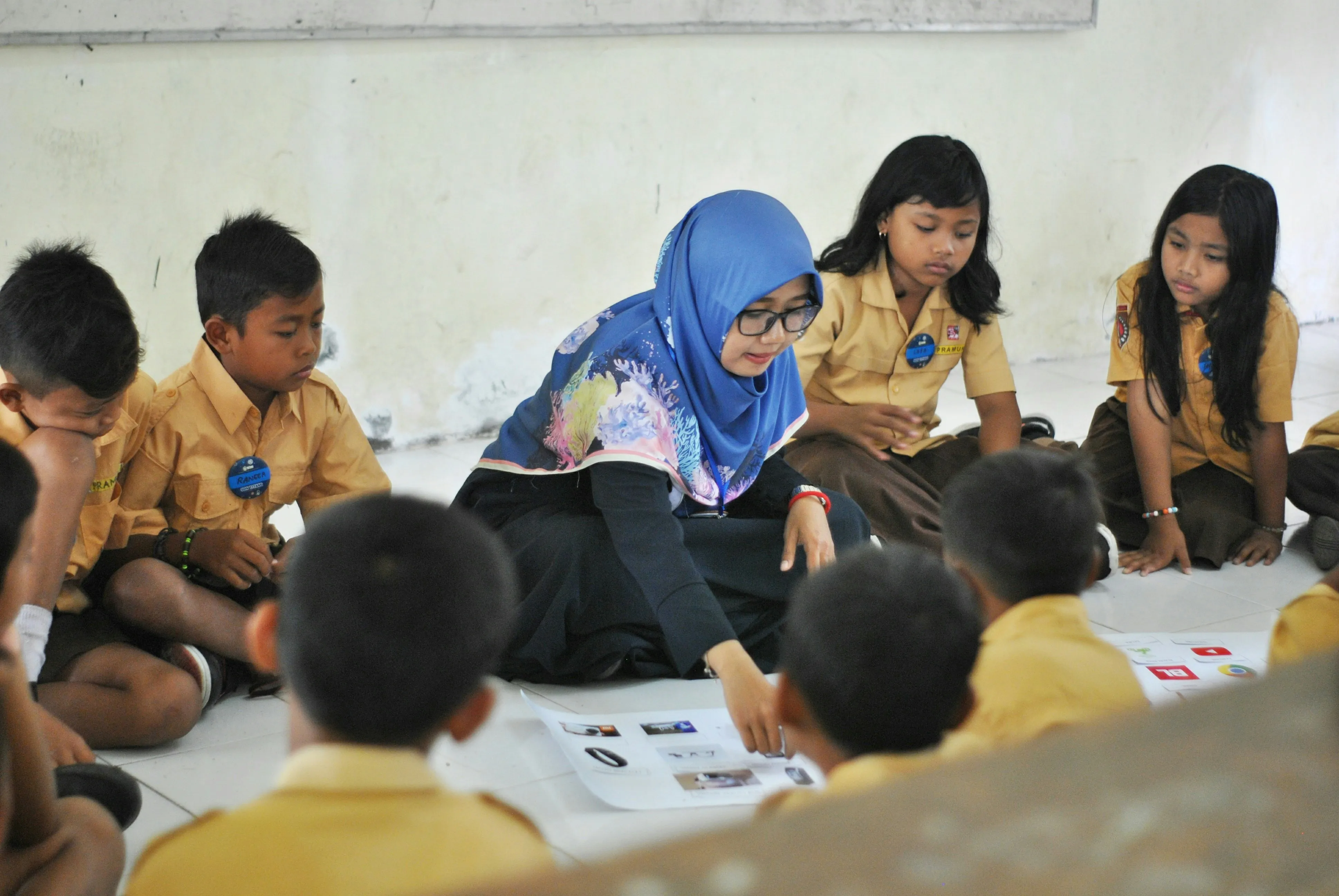 A teacher sitting on the floor with young students working on an activity