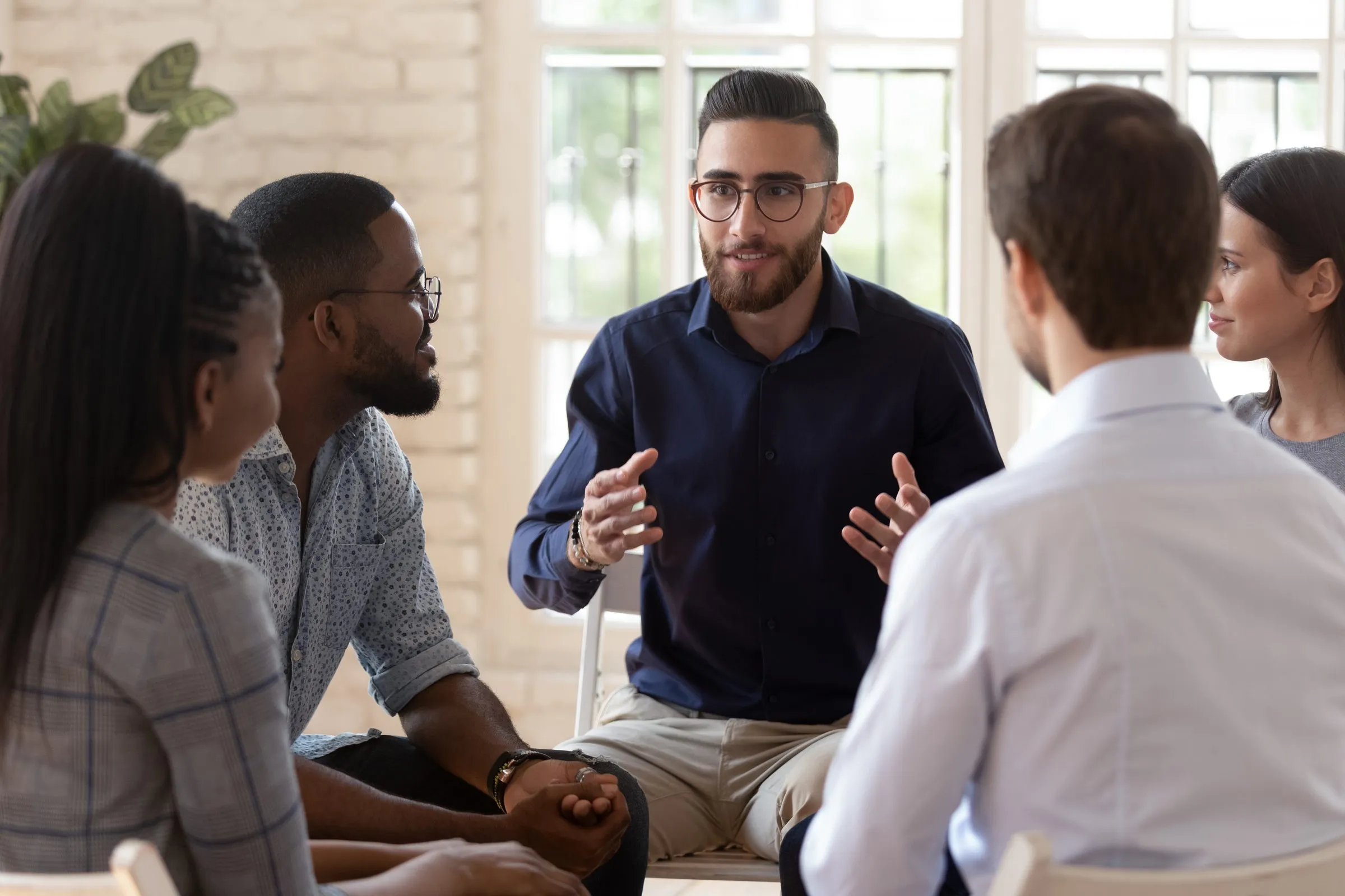 A man speaking to a small group seated in a circle