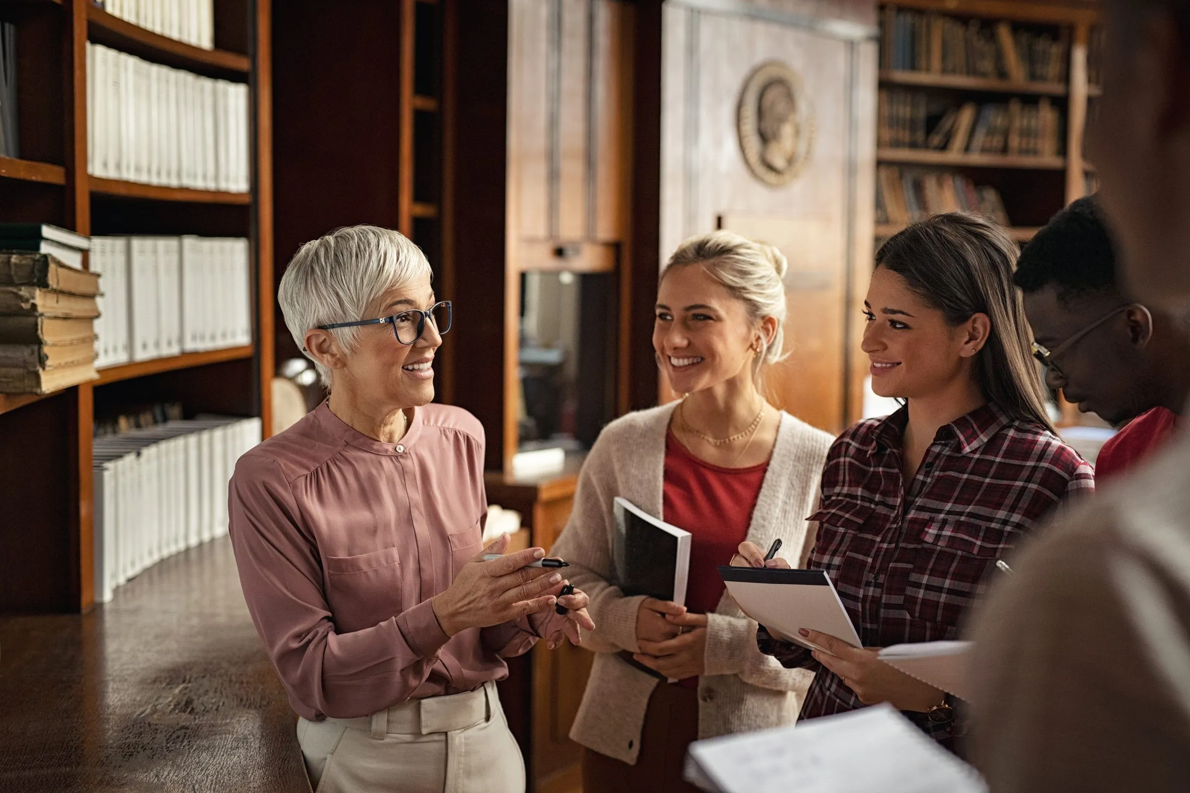 Three women in conversation among library shelves