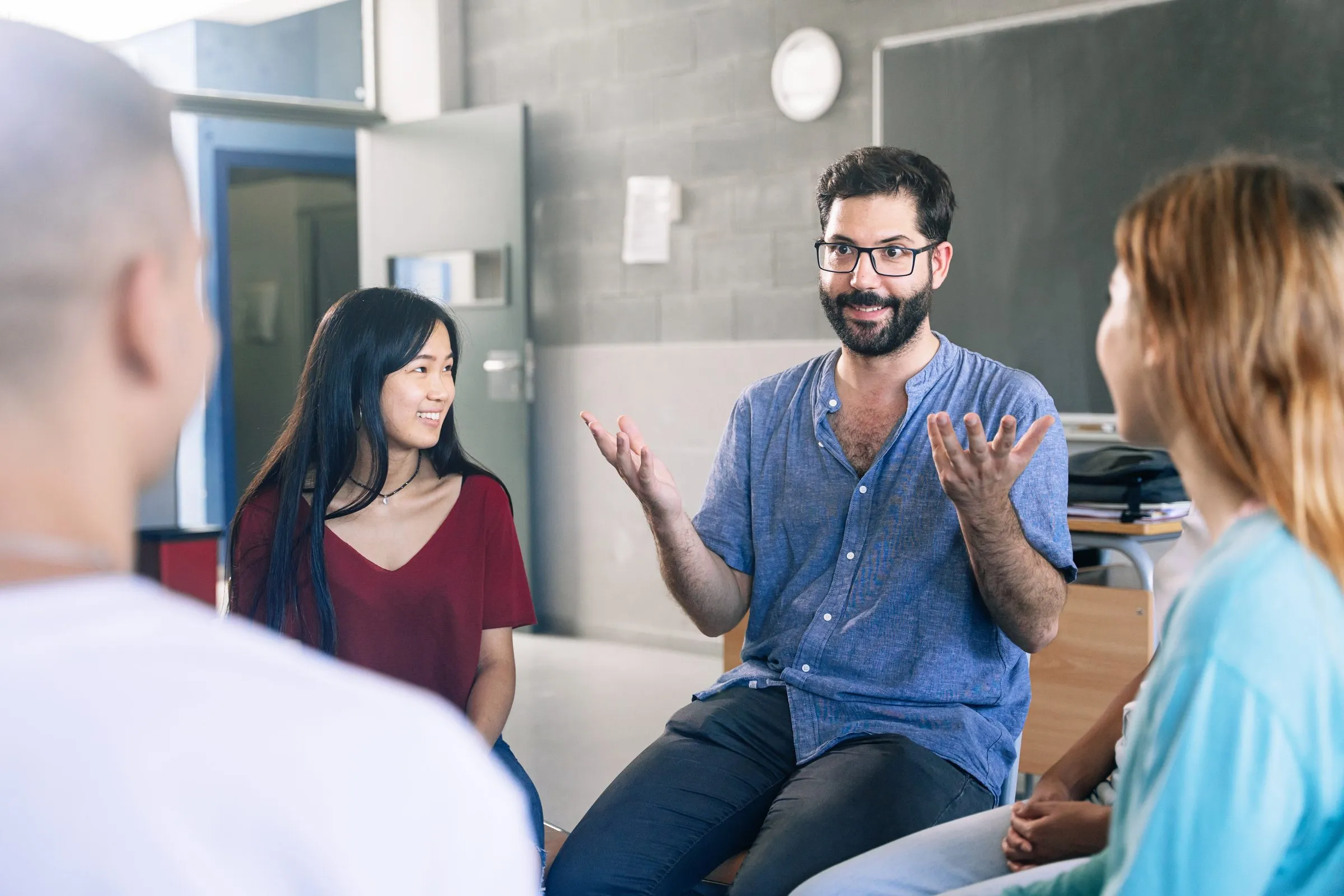 An educator in conversation with colleagues seated in a circle