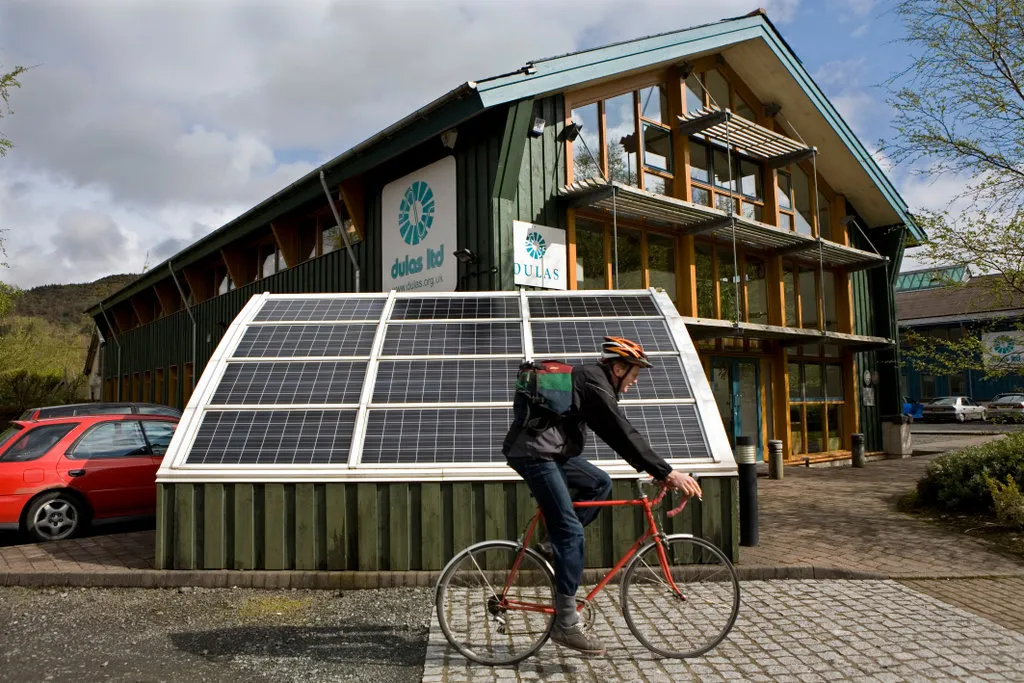 A person riding a bike beside a solar panel