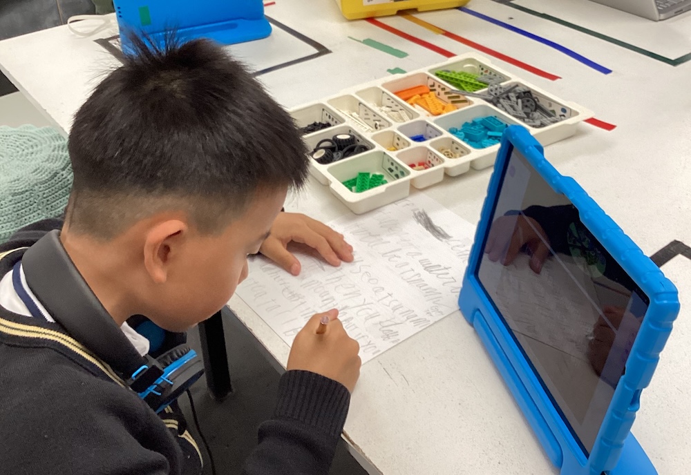 Young elementary student constructing and block coding a LEGO Education WeDo 2.0 beginner robot.