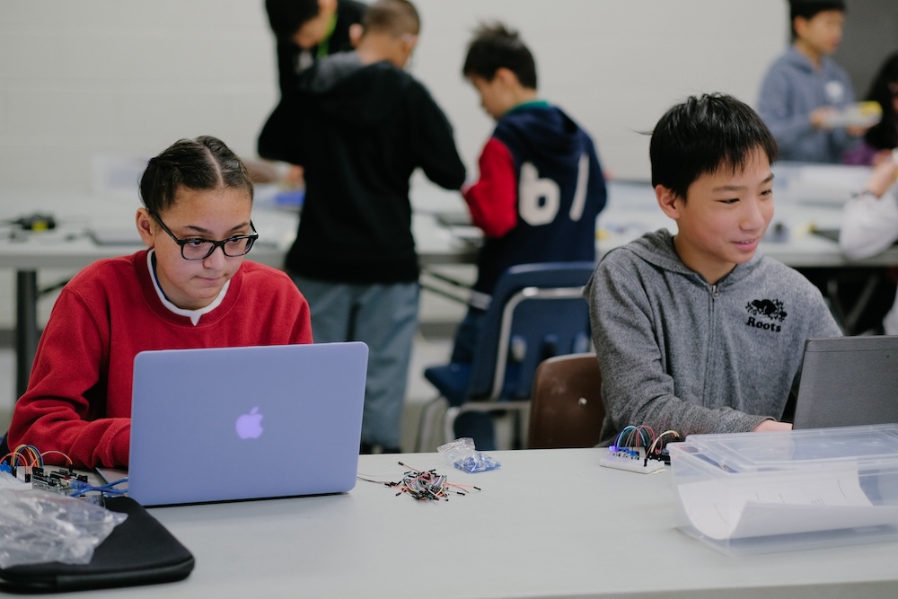 Student snapping colorful code blocks together on screen to create interactive games in Scratch.