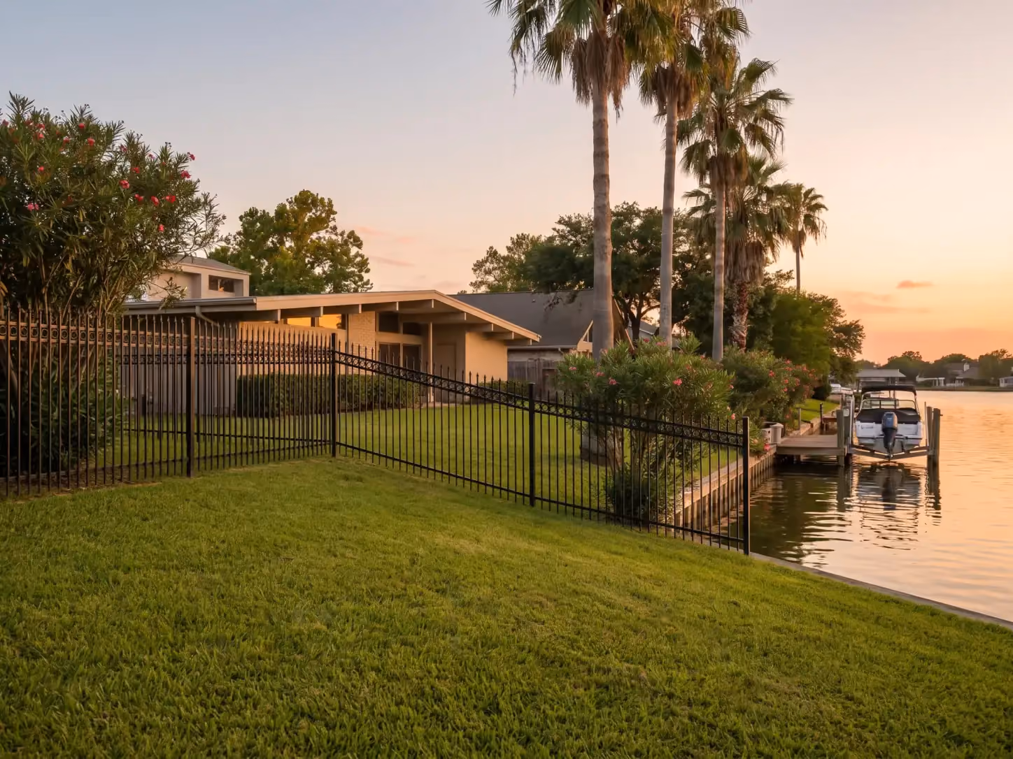 Black powder-coated wrought iron fence along a lagoon-front backyard and private dock in Nassau Bay, TX