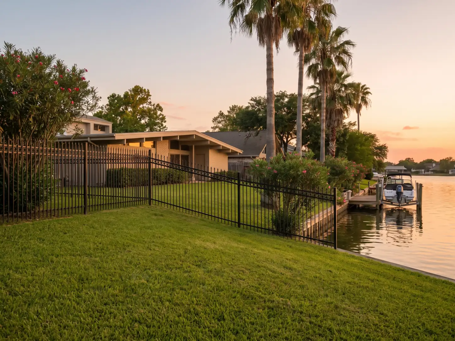 Black powder-coated wrought iron fence along a lagoon-front backyard and private dock in Nassau Bay, TX