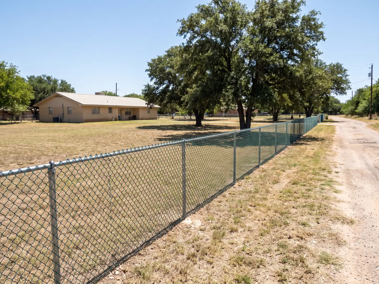 Galvanized chain link fence along a large Texas backyard, the lowest-cost fencing option