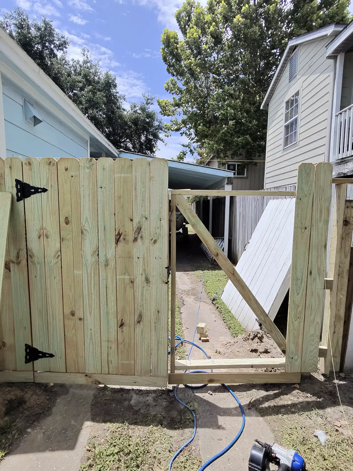 A cedar gate frame with a diagonal brace is installed between fence posts in a side yard in Pearland, TX.