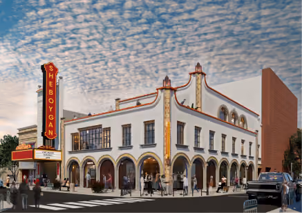Corner view of Sheboygan theater building with vintage sign and blue sky with scattered clouds.