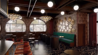Indoor rooftop patio with green bench seating, wooden tables, red stools, round windows, and chandeliers.