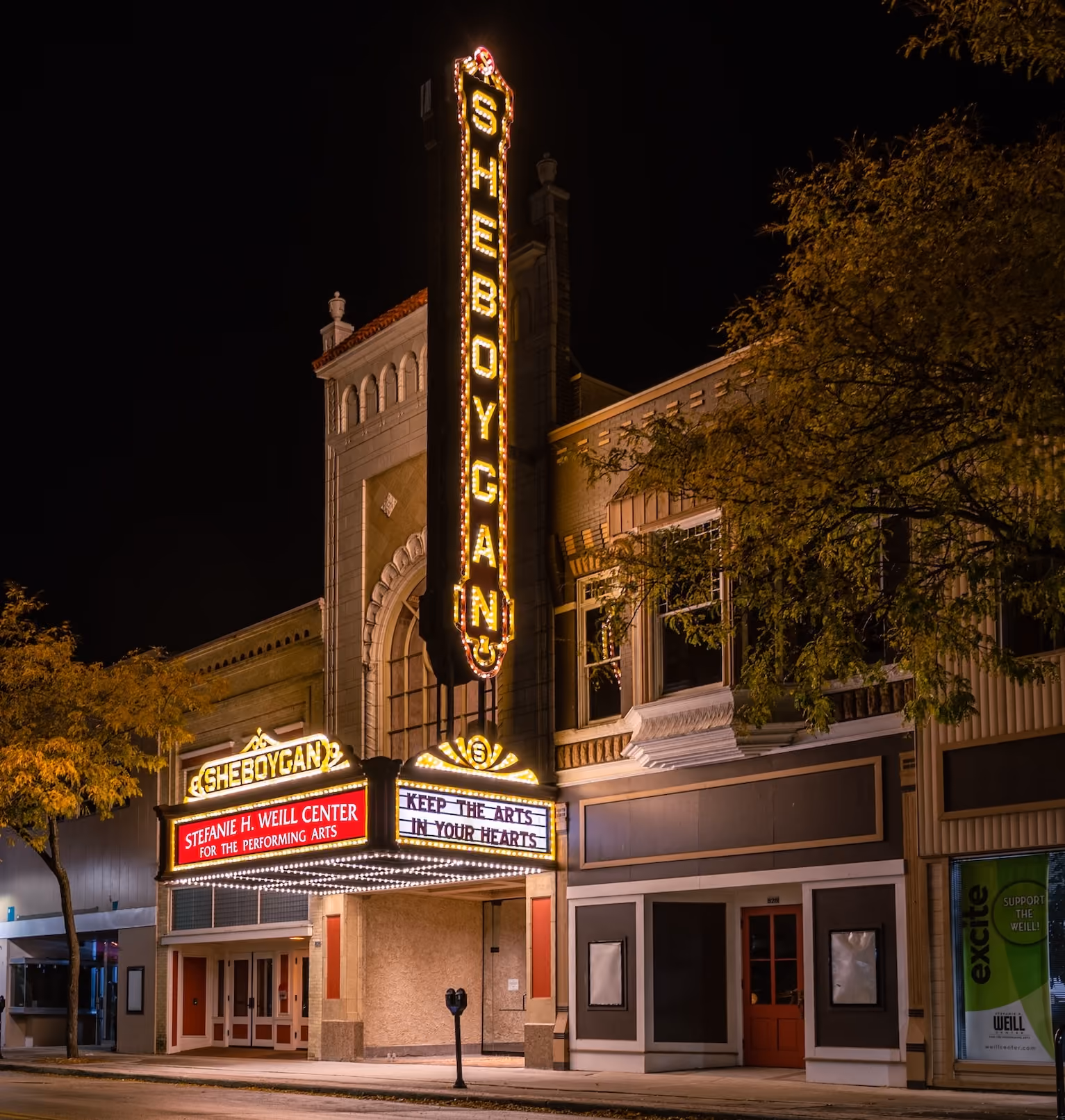 Night view of Sheboygan theater marquee lit with lights and signs for Weill Center and performing arts.