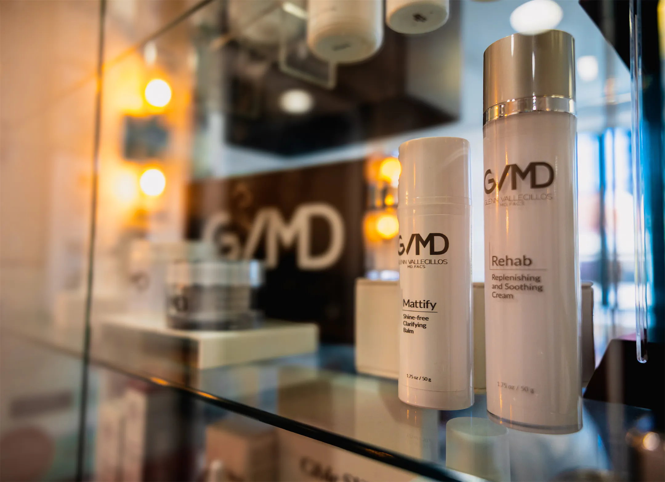 GVMD-branded skincare products on a glass shelf with the GVMD logo behind